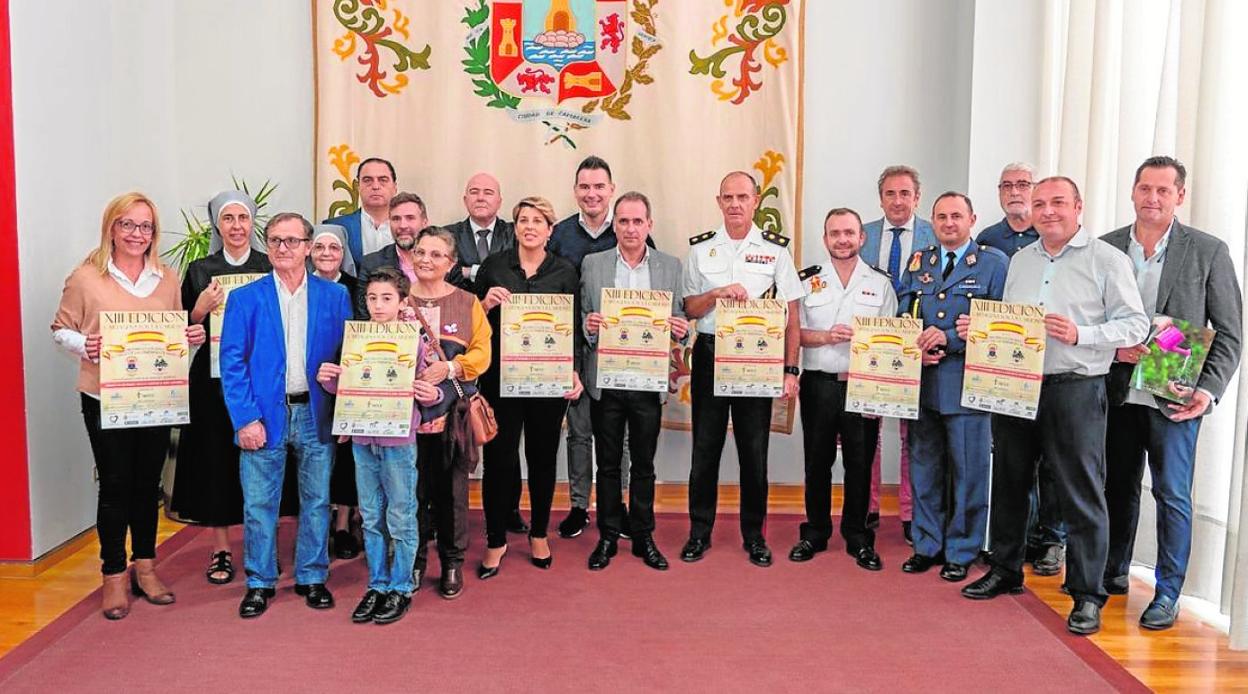 Participantes en la presentación del evento solidario, mostrando el cartel. 