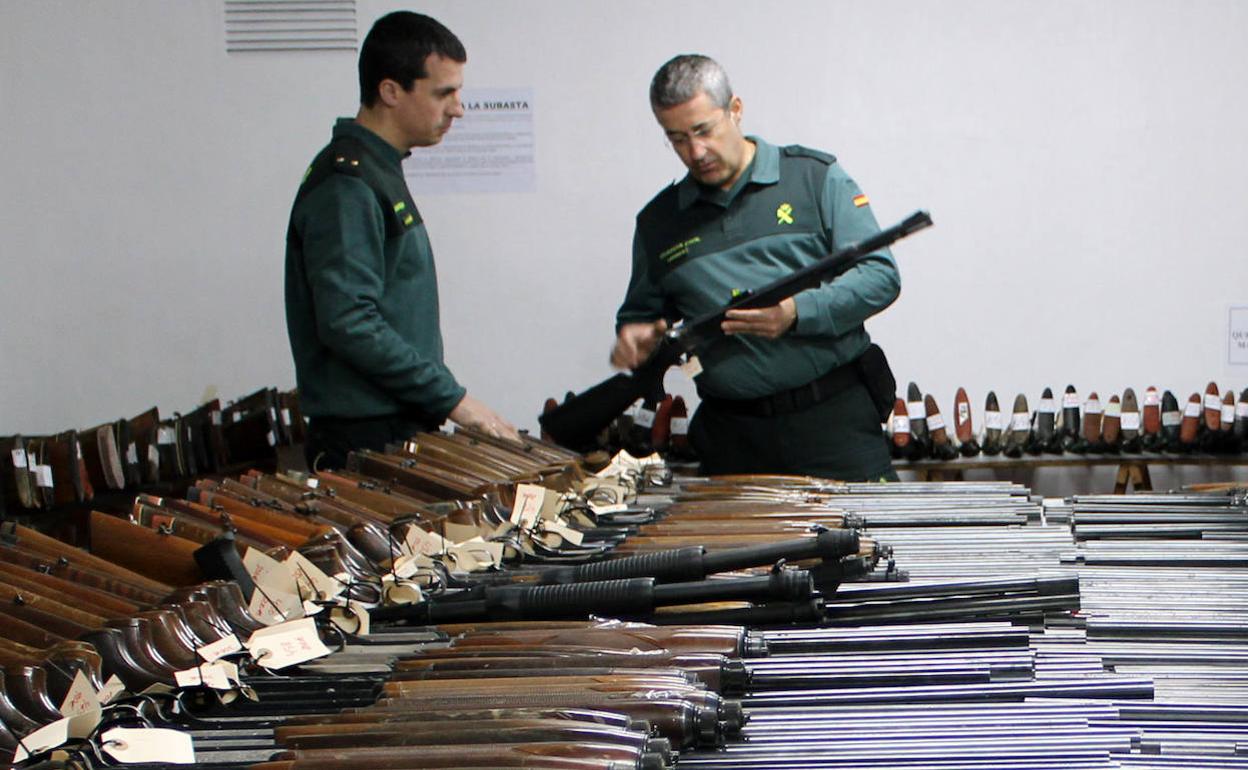 Dos agentes de la Benemérita, junto a las armas que se subastarán a partir del lunes 25 de noviembre.