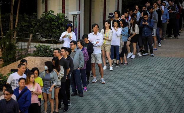 Decenas de hongkoneses hacen cola para ejercer su derecho a voto en las elecciones municipales celebradas este domingo.