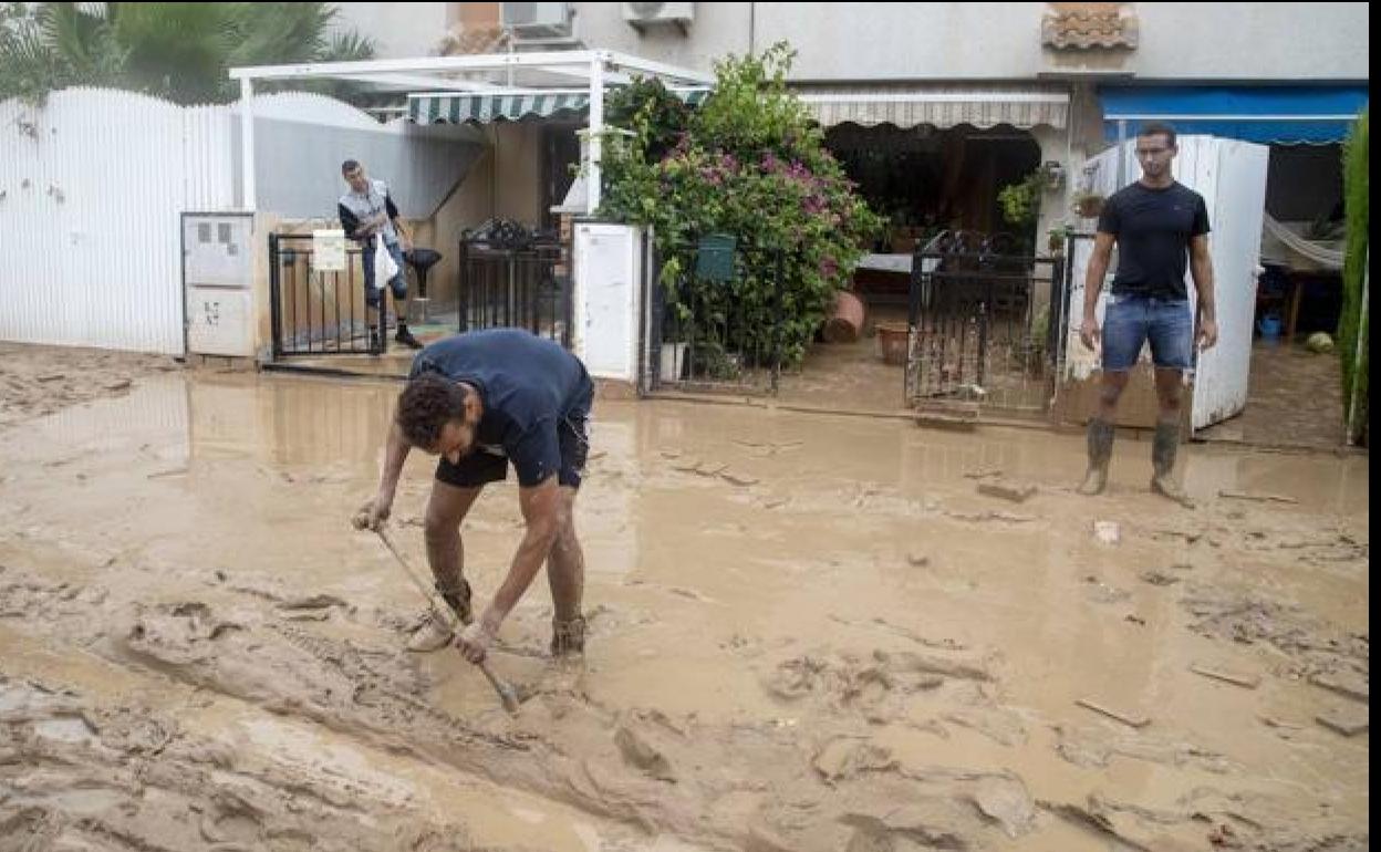 Dos personas retirando barro en una calle de Los Alcázares afectada por las inundaciones del pasado mes de septiembre.