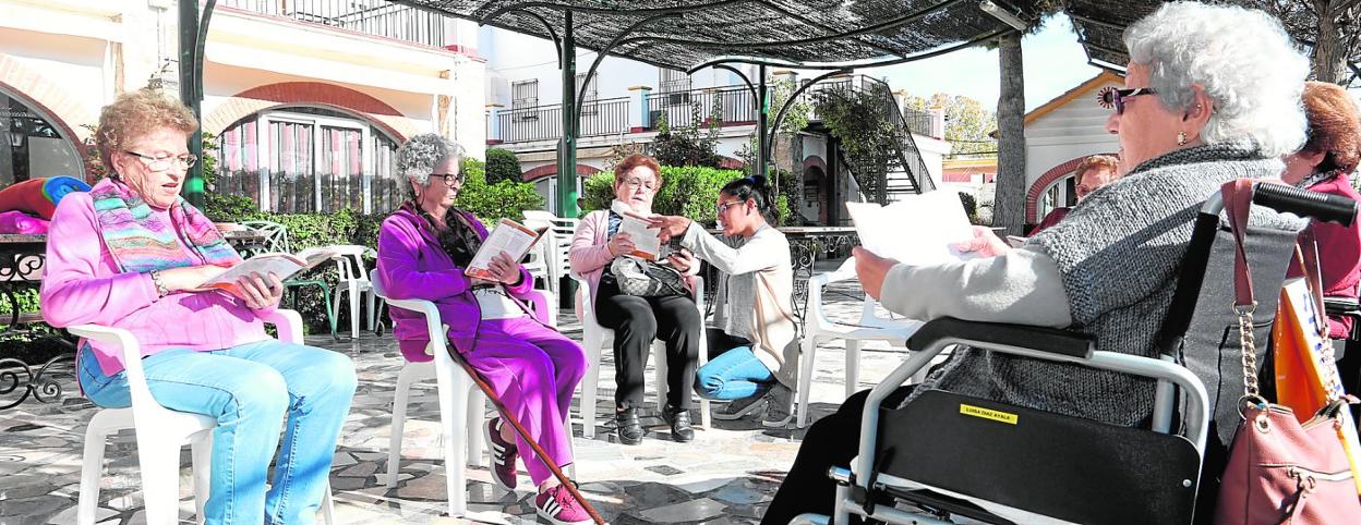 Melina, rodeada de ancianas, ayuda en la lectura a María de los Ángeles durante la realización del taller semanal en la residencia San Diego. 