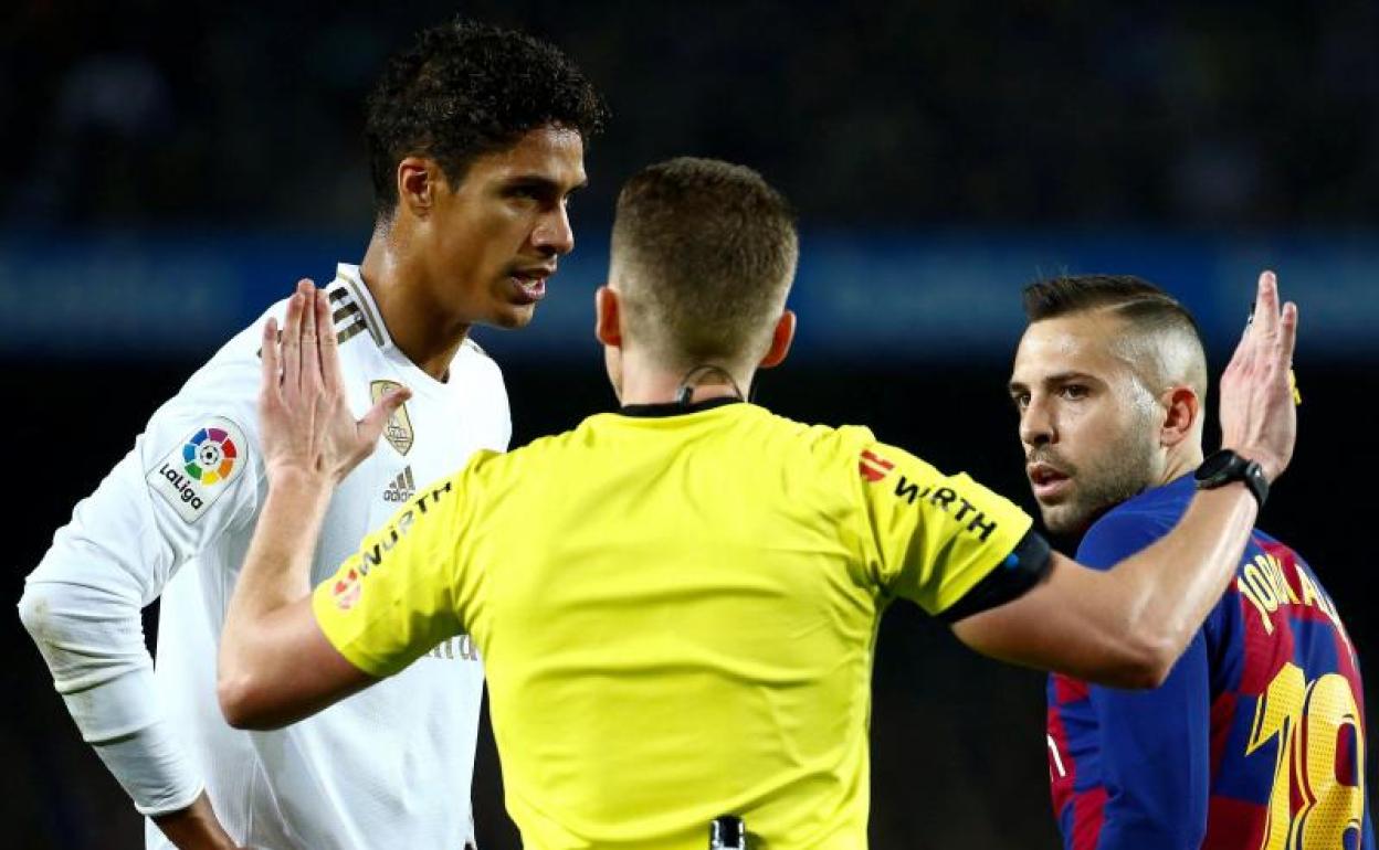 Raphael Varane y Jordi Alba, junto al árbitro del clásico. 