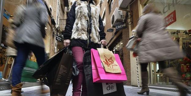 Varias personas hacen sus compras en una concurrida calle llena de comercios. 