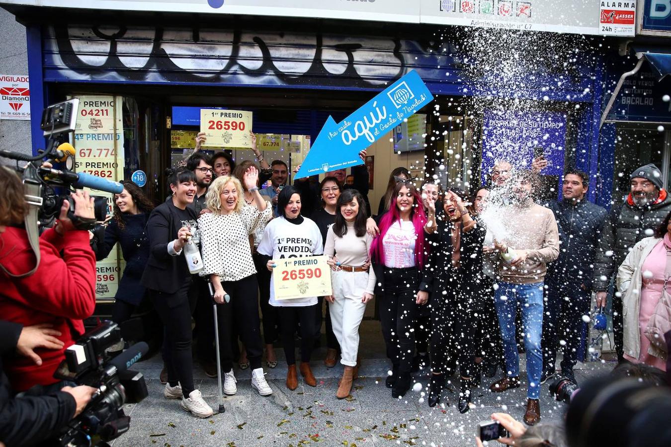 Un grupo de personas celebran en la administración madrileña de Doña Manolita que ha vendido el número 26.590