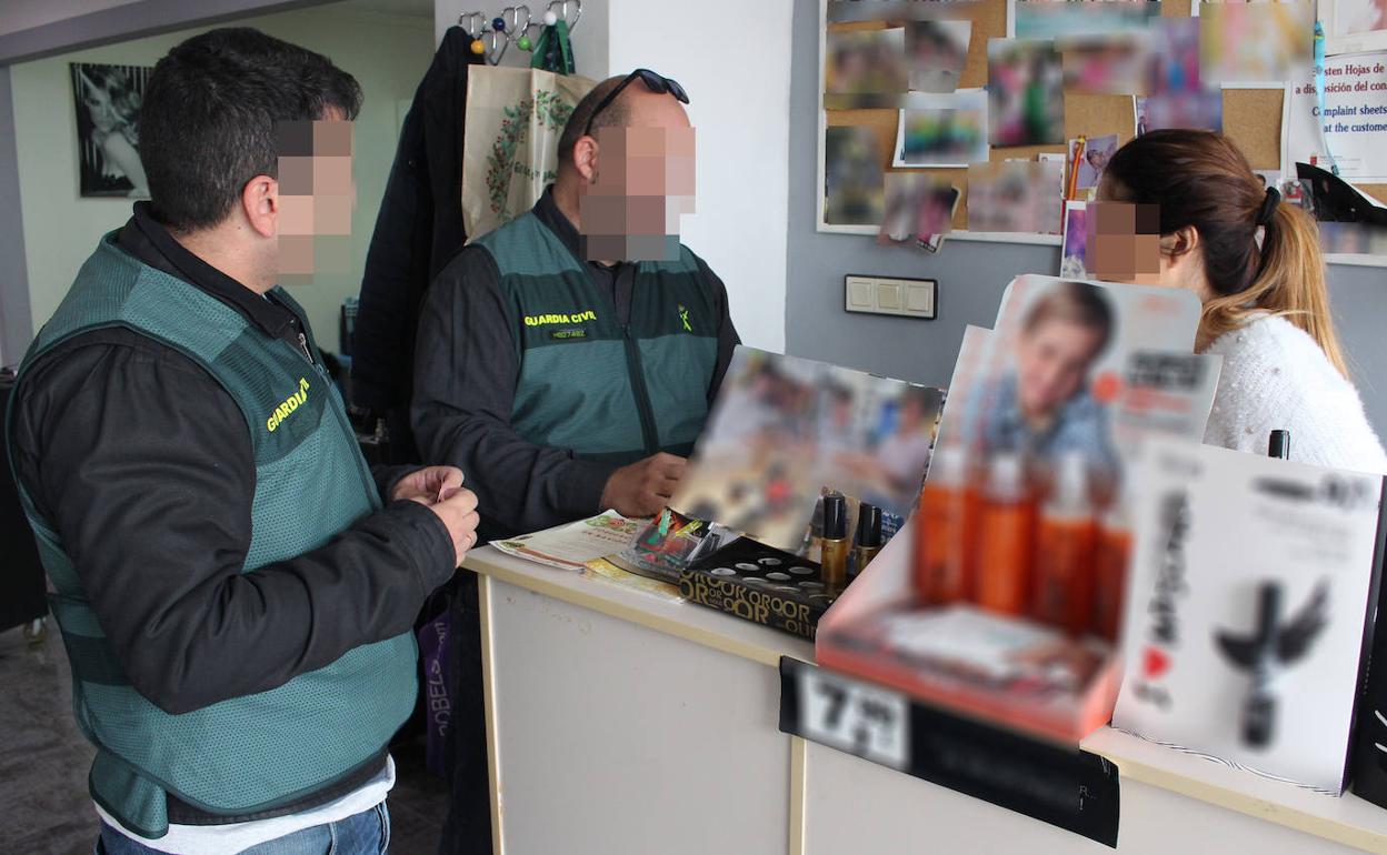 Dos agentes de la Guardia Civil junto a una de las peluqueras que fue víctima de los robos.