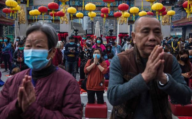 Personas rezan con mascarillas en Hong Kong.