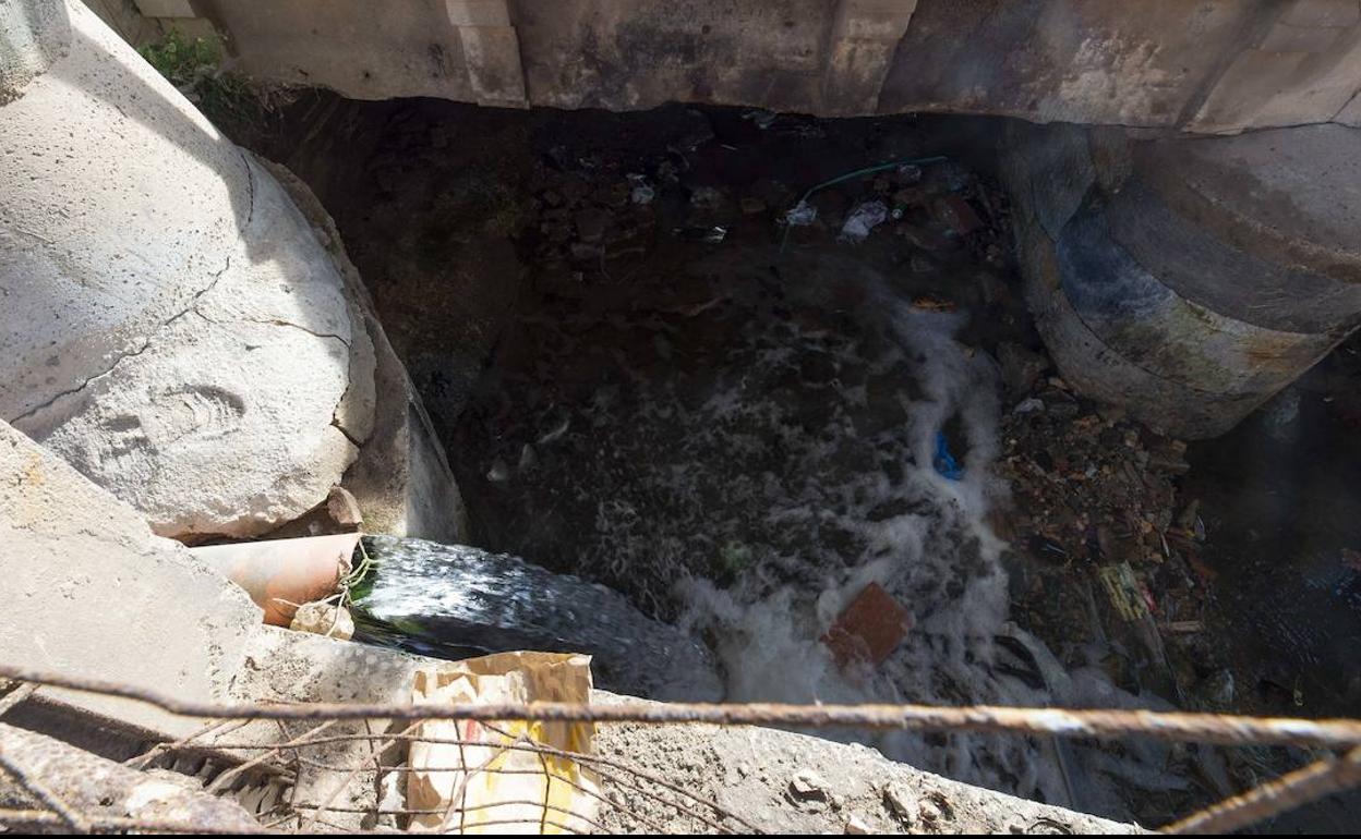 Una tubería echa agua al lado del puente de El Hondón.