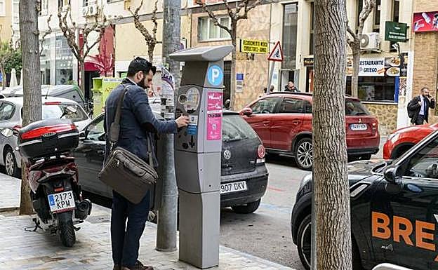 Un hombre paga la ORA en una calle de Murcia.