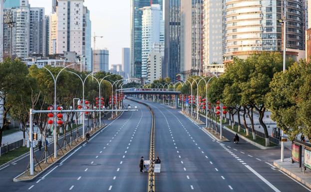 Dos personas atraviesan una avenida completamente vacía para llevar unas cajas de verduras a un hospital, en Wuhan (China), epicentro de la epidemia.