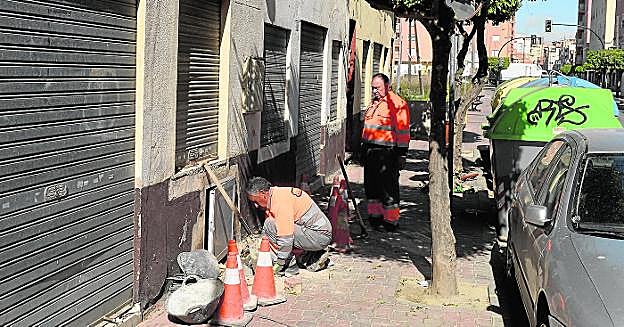 Dos operarios cortan el agua después de que unos okupas se engancharan ilegalmente a la red. 