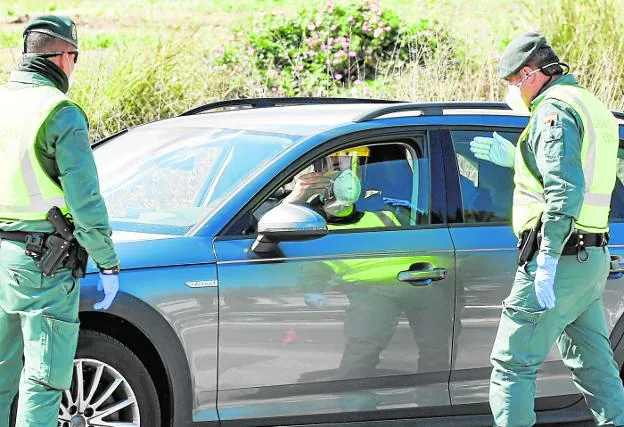 Un conductor muestra su documentación a los agentes tras la ventanilla de su vehículo. 