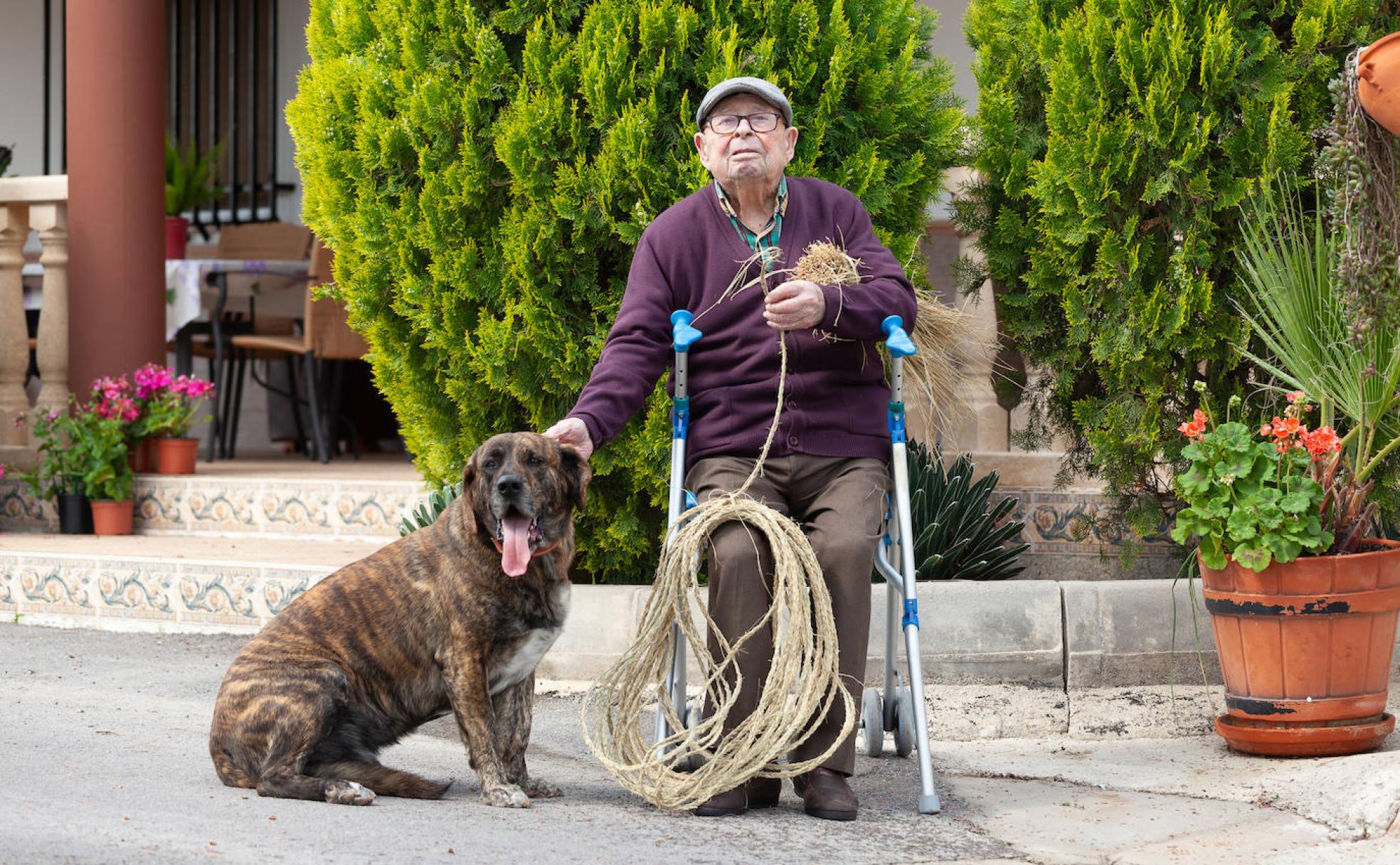 José trenza esparto junto a su fiel perro 'León' en el jardín de la casa familiar de La Hoya. 