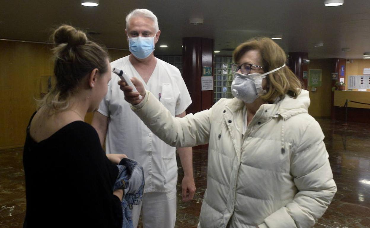 Dos sanitarios toman la temperatura a una mujer en el hospital La Arrixaca, el pasado domingo.