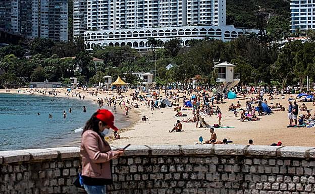 Una playa en Hong Kong, donde los bañistas vuelven a la arena. aunque algunos ciudadanos no se quitan la mascarilla.