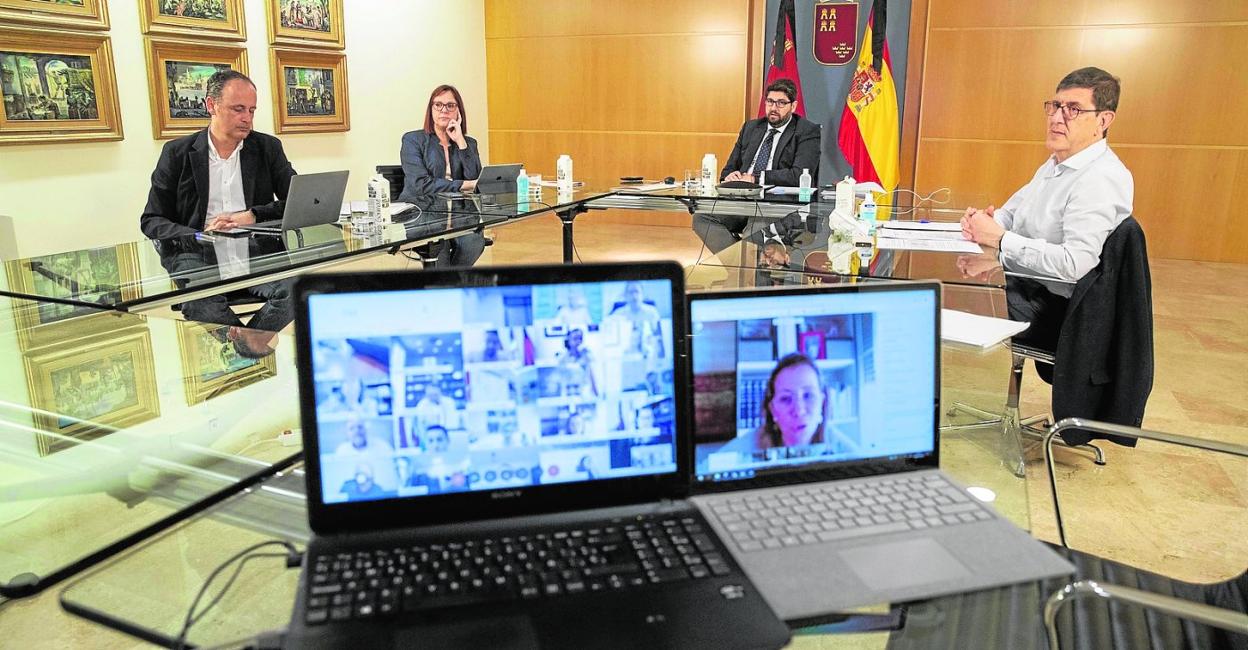 Celdrán, Franco, López Miras y Villegas escuchan a Ana Belén Castejón, cuya imagen se refleja en el ordenador de la derecha. 