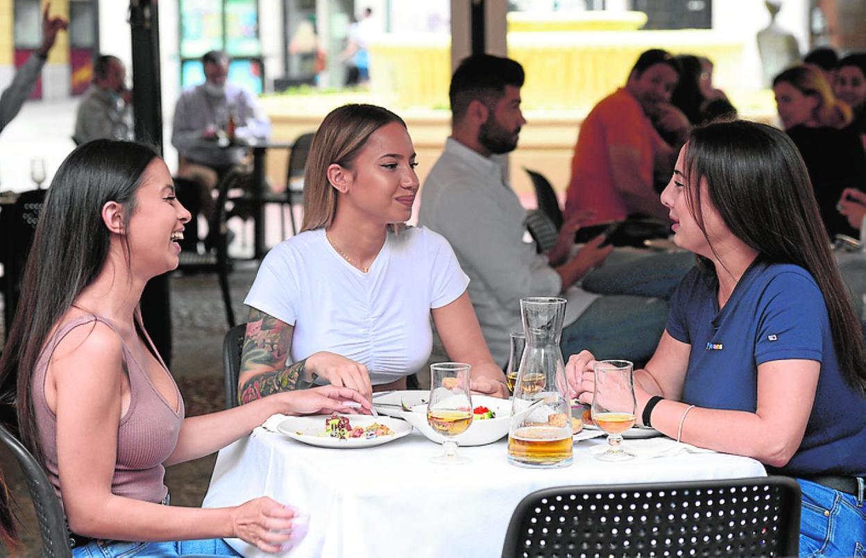 Tres jóvenes disfrutan de un aperitivo en Murcia. 