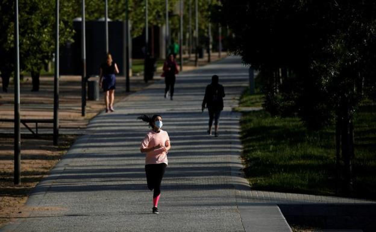Una mujer practicando deporte con mascarilla.