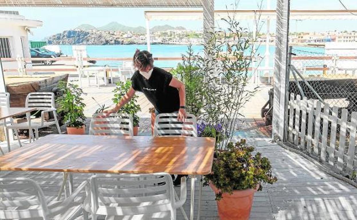 Una empleada prepara la terraza de un bar de Cabo de Palos.