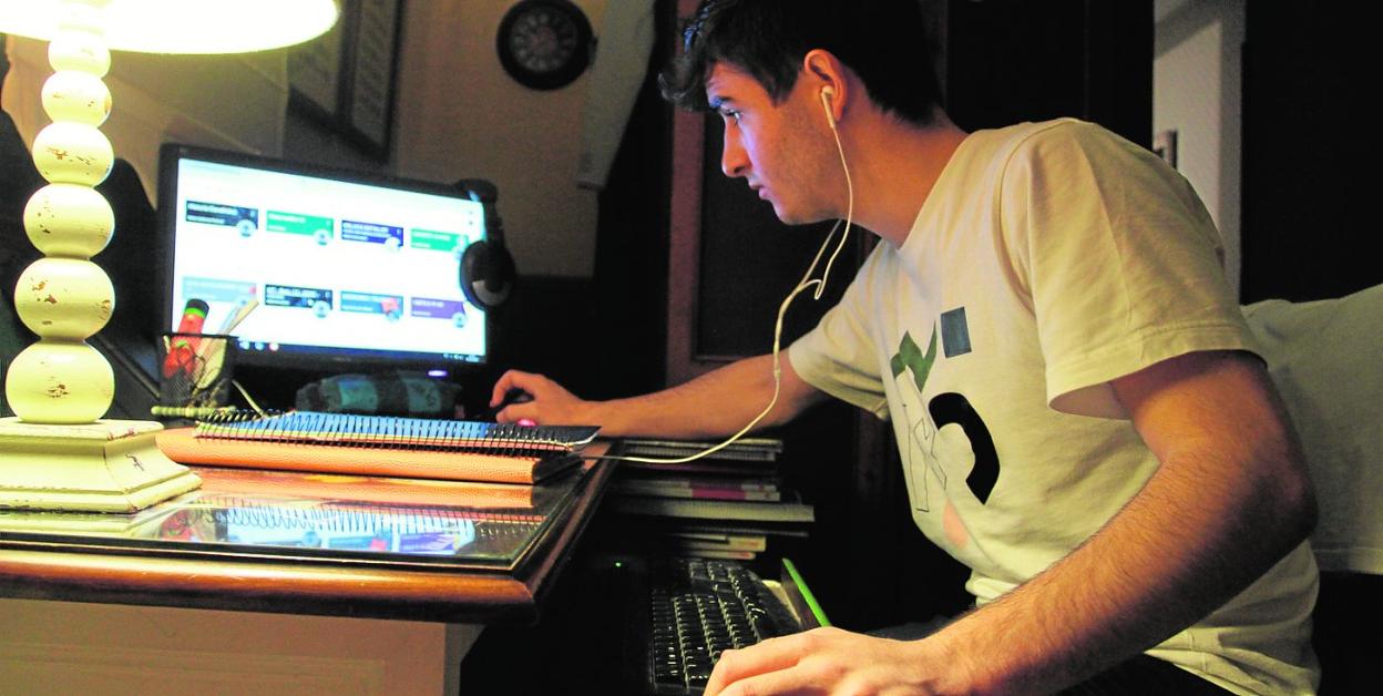 Un universitario sigue las clases en casa por internet. 
