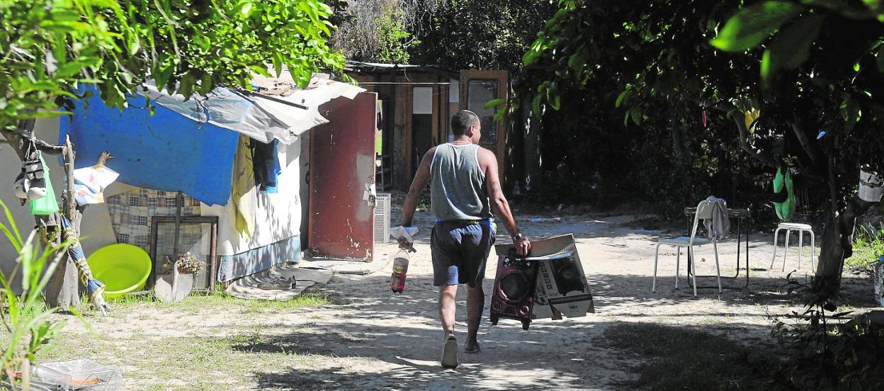 Un hombre transporta varios objetos en un asentamiento de la pedanía murciana de Patiño. 