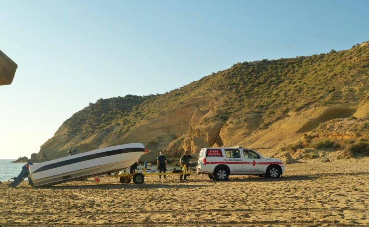 Dos agentes remolcan la patera que llegó a la costa de Águilas este lunes. 