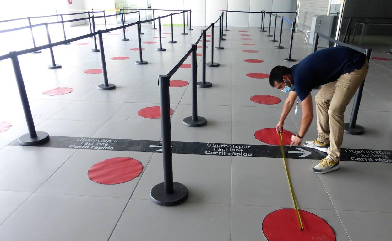 Un operario instala marcas para garantizar la seguridad en las colas.