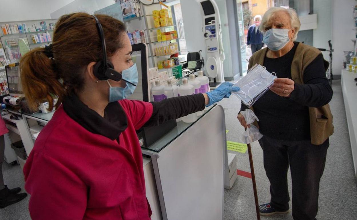 Una mujer recogiendo una mascarilla en una farmacia de Murcia en una foto de archivo.