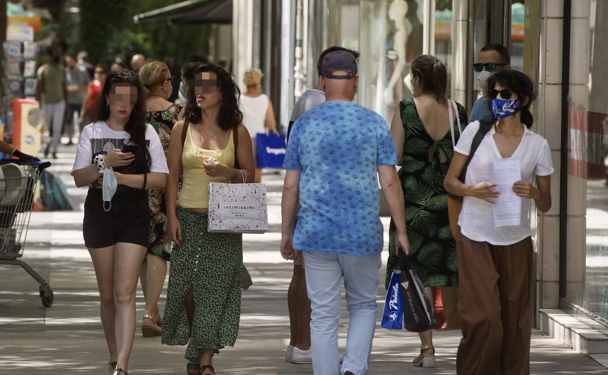 Varias personas con y sin mascarilla caminan por una calle de Murcia en una foto de archivo. 