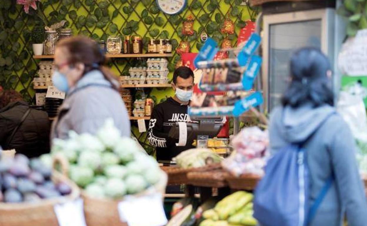 Empleados y clientes de una frutería con mascarilla.