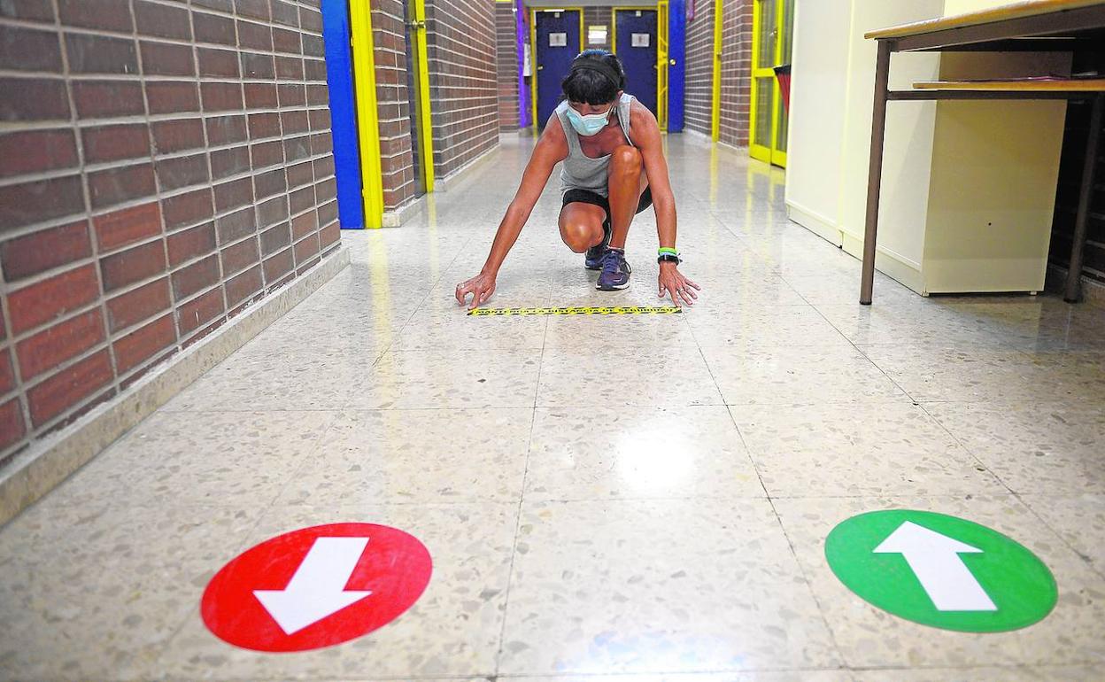 Una empleada del colegio Federico Arce de Murcia coloca señales en uno de los pasillos.