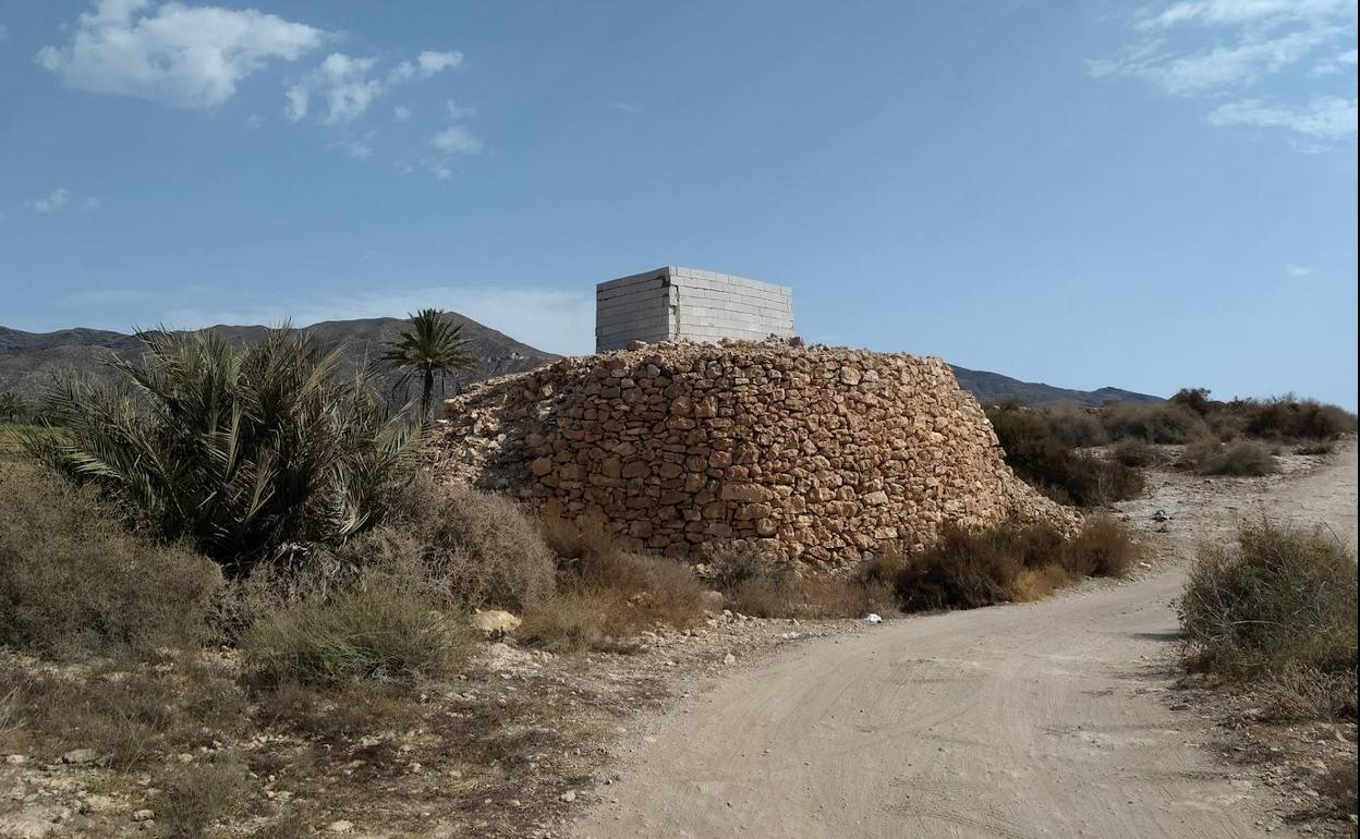 Estructura de piedra caliza de la noria de Cala Blanca, cubierta con bloques de hormigón. 