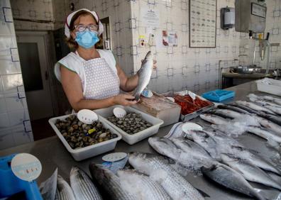 Imagen secundaria 1 - 1- María García enseña una lubina, tras el mostrador de la pescadería Félix. 2- Severo Martínez muestra un racimo de uva en la frutería de Ramón González.