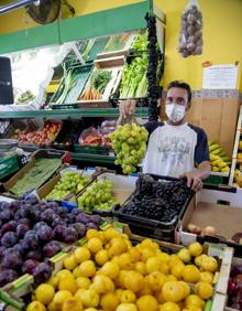 Imagen secundaria 2 - 1- María García enseña una lubina, tras el mostrador de la pescadería Félix. 2- Severo Martínez muestra un racimo de uva en la frutería de Ramón González.