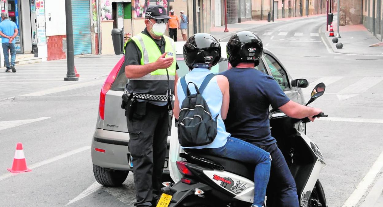 Un agente comprueba que los ocupantes de una moto cumplen con las restricciones impuestas por la pandemia.