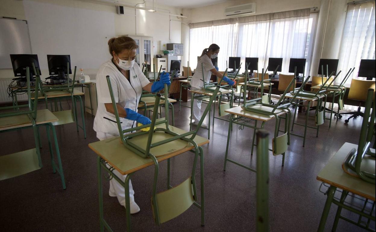 Personal de limpieza prepara una clase para el comienzo del curso en un instituto de la Región. 