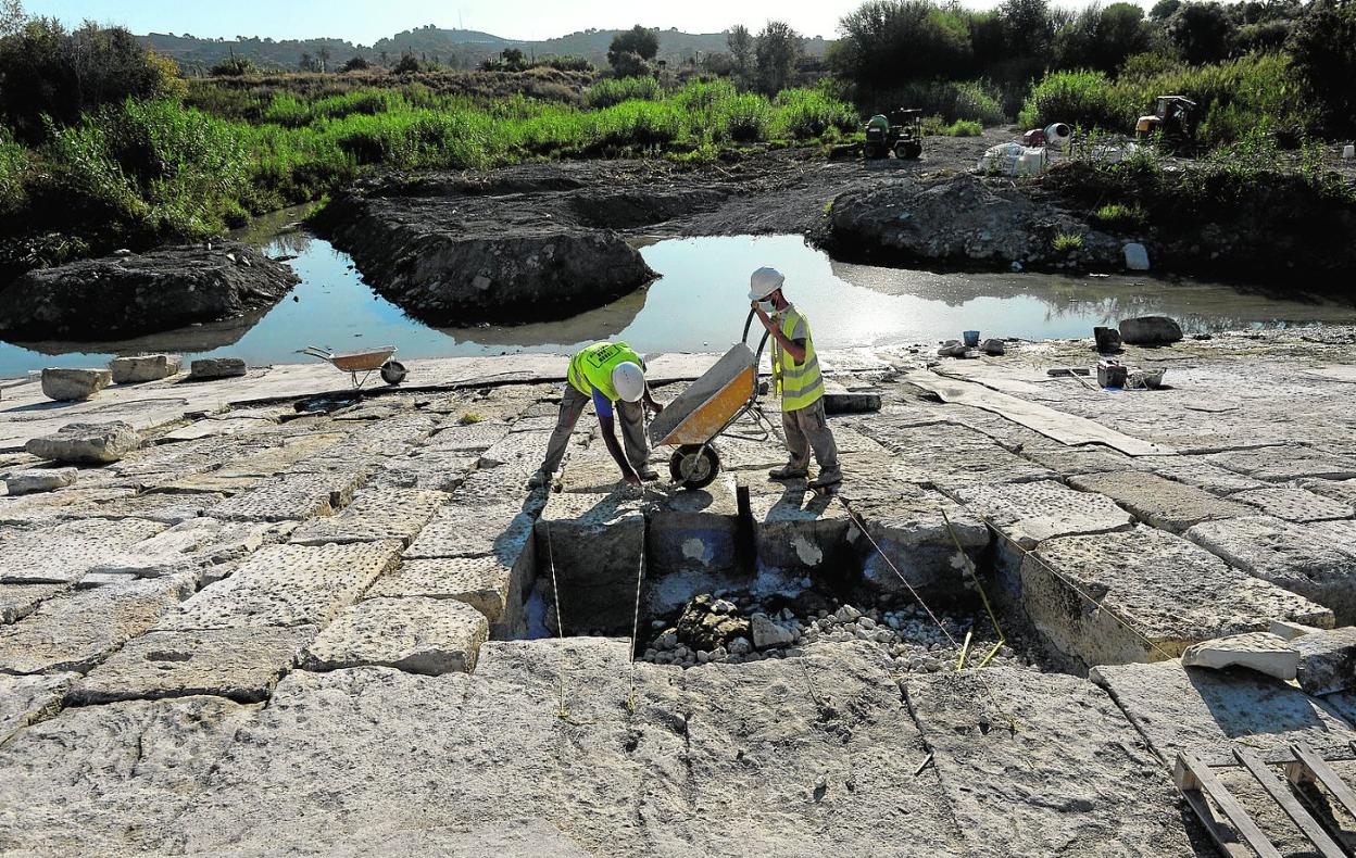 Dos trabajadores rellenan las juntas de los últimos sillares que quedan por recolocar en la presa de La Contraparada. 