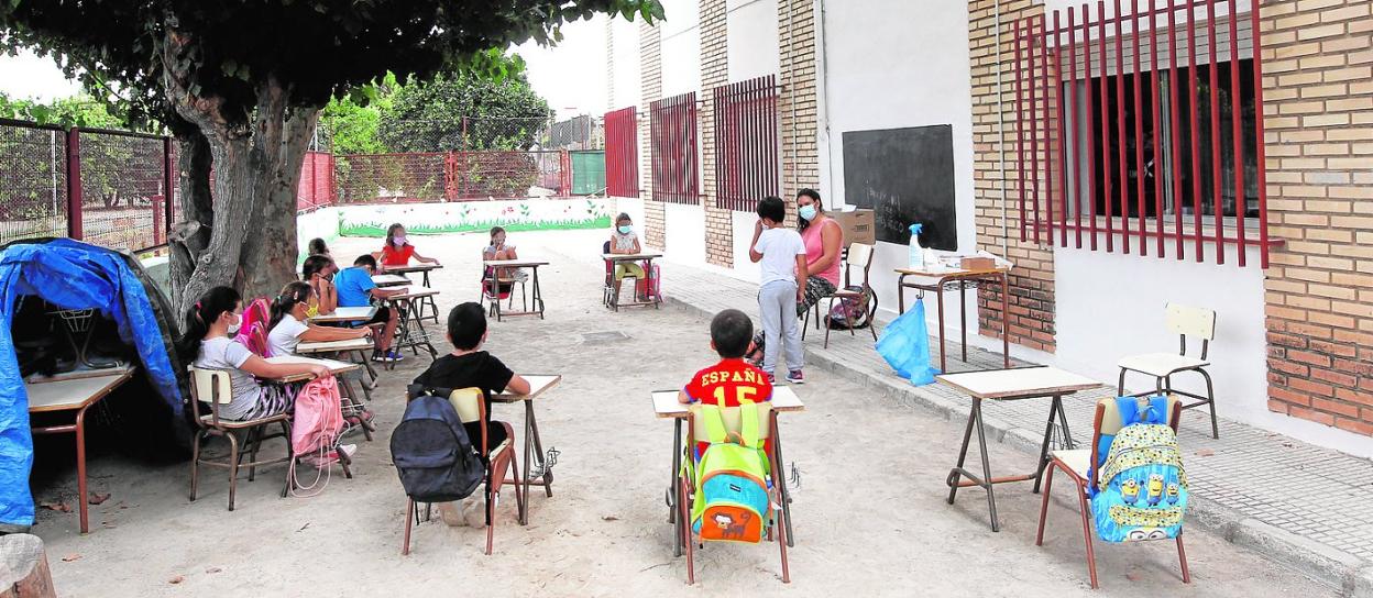 Alumnos del colegio Puente de Doñana, en la pedanía murciana de La Albatalía, en plena clase a la sombra de un árbol. 