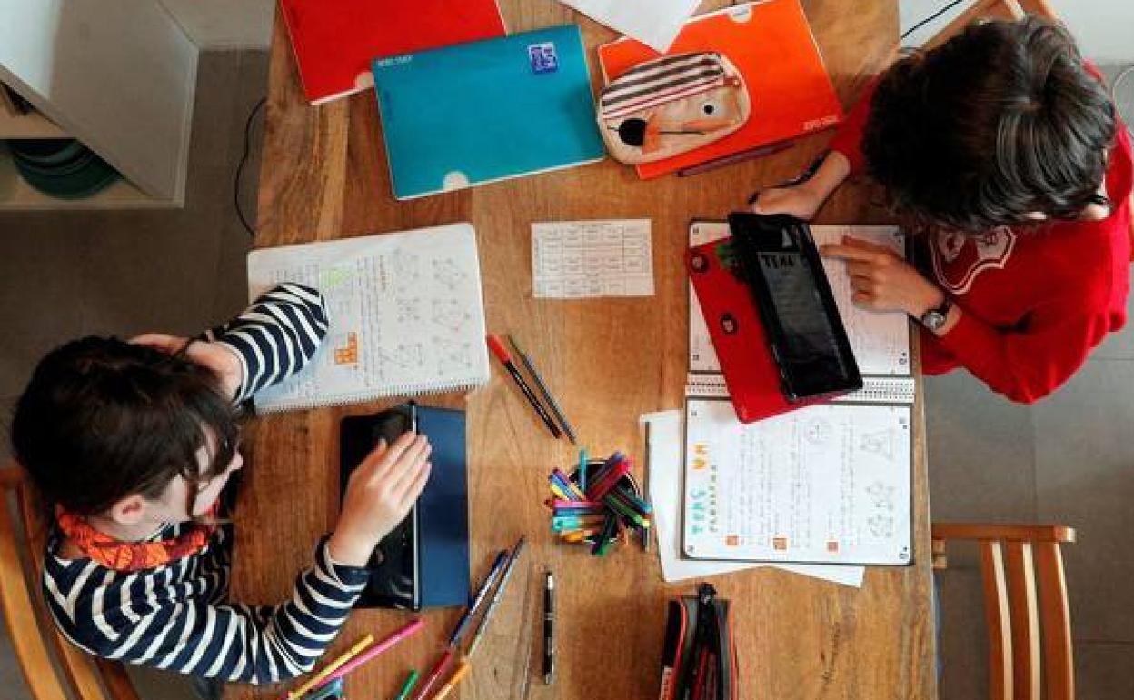 Dos niños asisten a clases telemáticas en su domicilio.