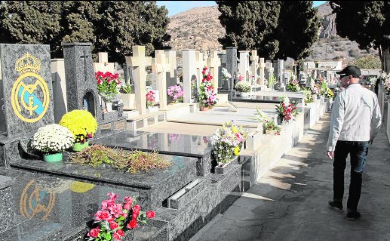 Un hombre pasa ante varias tumbas adornadas con flores, en el cementerio de Santa Lucía.