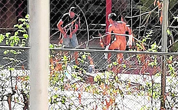 Dos indigentes se asean, uno de ellos desnudo, a plena luz del día, en el recinto de la antigua guardería.