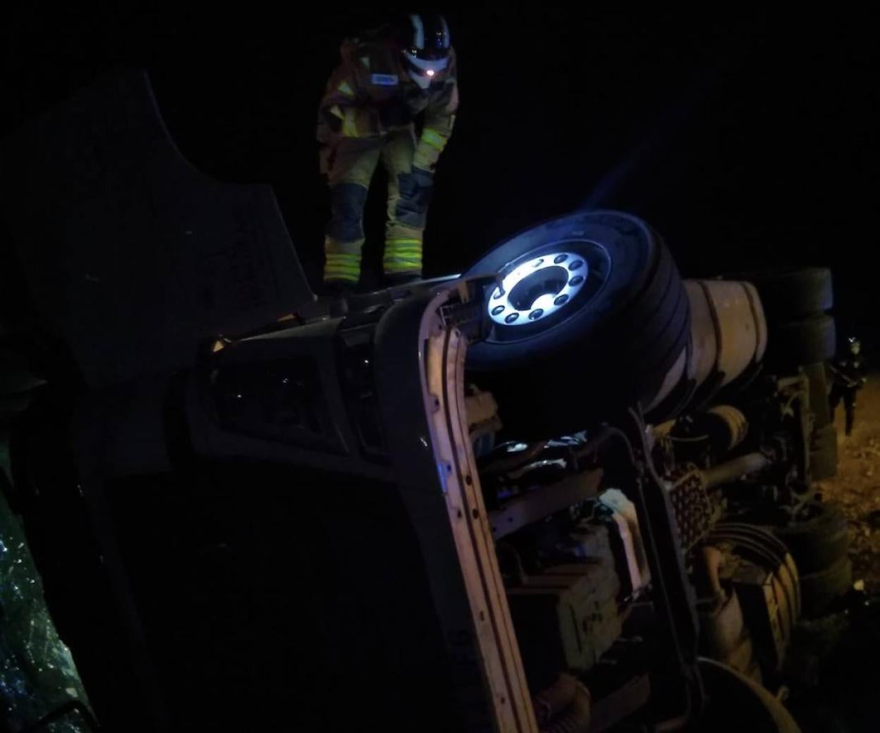 Un bombero observa el camión volcado.