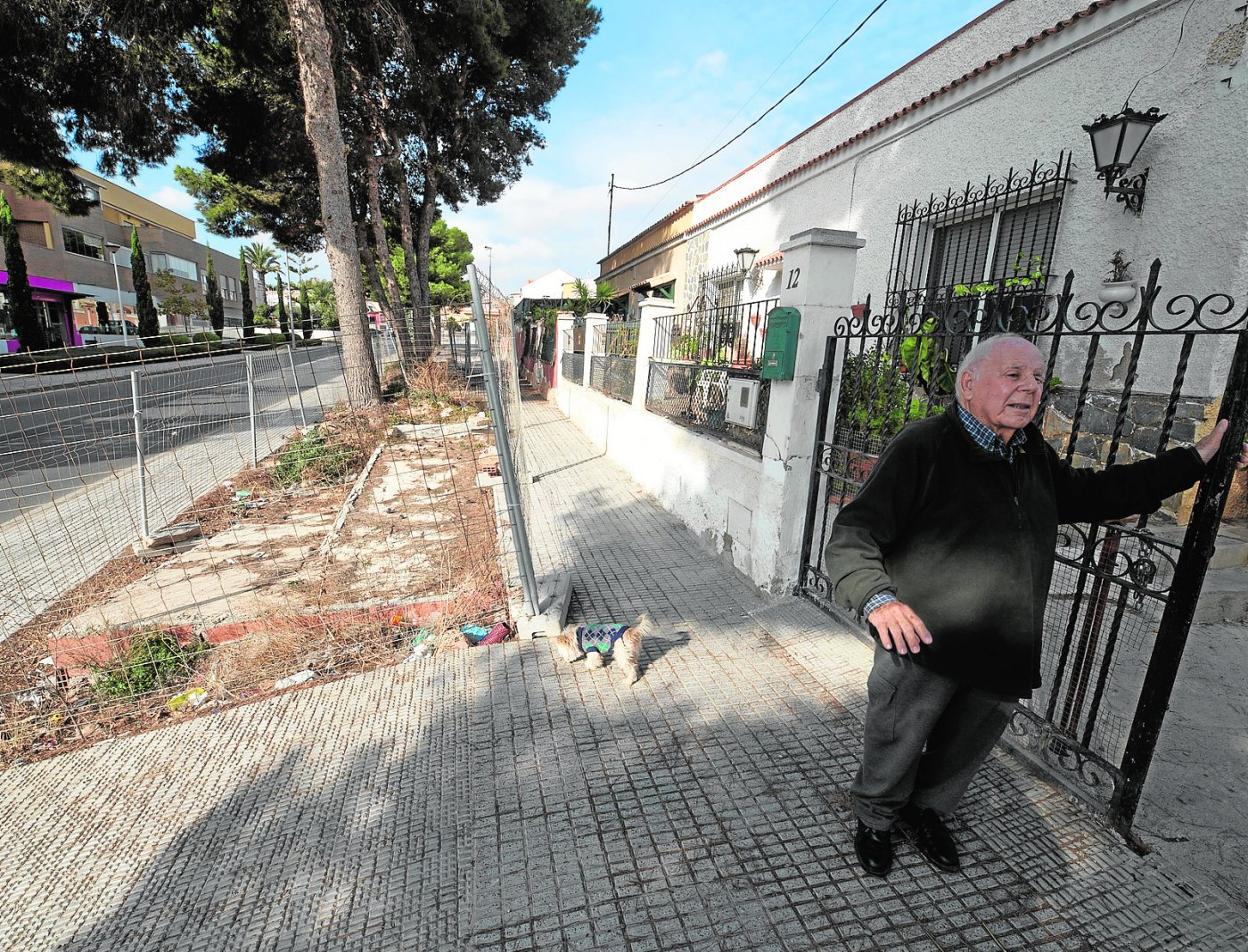 José García, apoyado en la puerta de su vivienda, junto a la obra inacabada, en la calle Mayor de Canteras. 