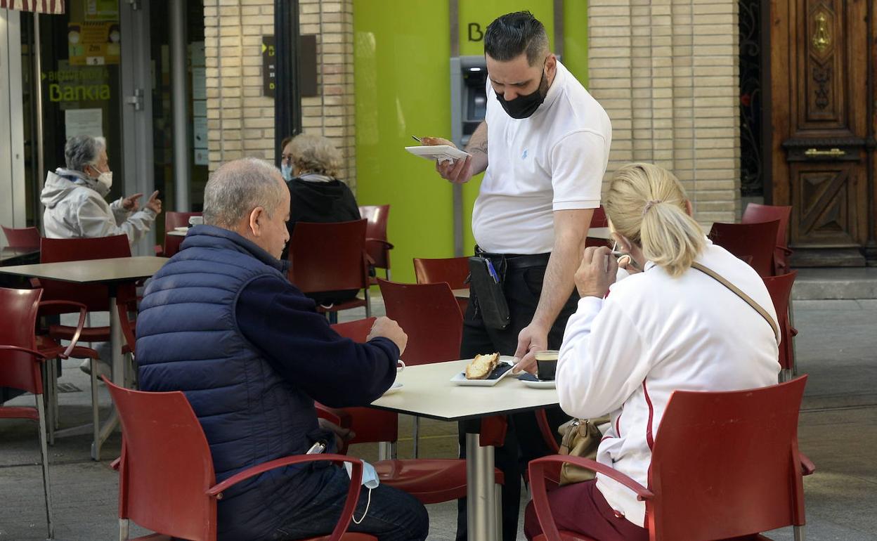 Un camarero atiende a unos clientes en una terraza de Murcia.