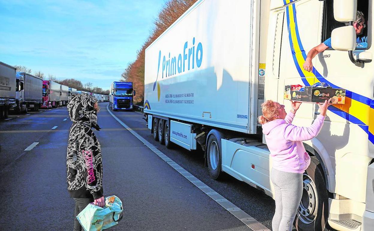 Una mujer ofrece una bandeja de comida al ocupante de un camión de la empresa murciana Primafrio atrapado en la frontera entre Reino Unido y Francia.
