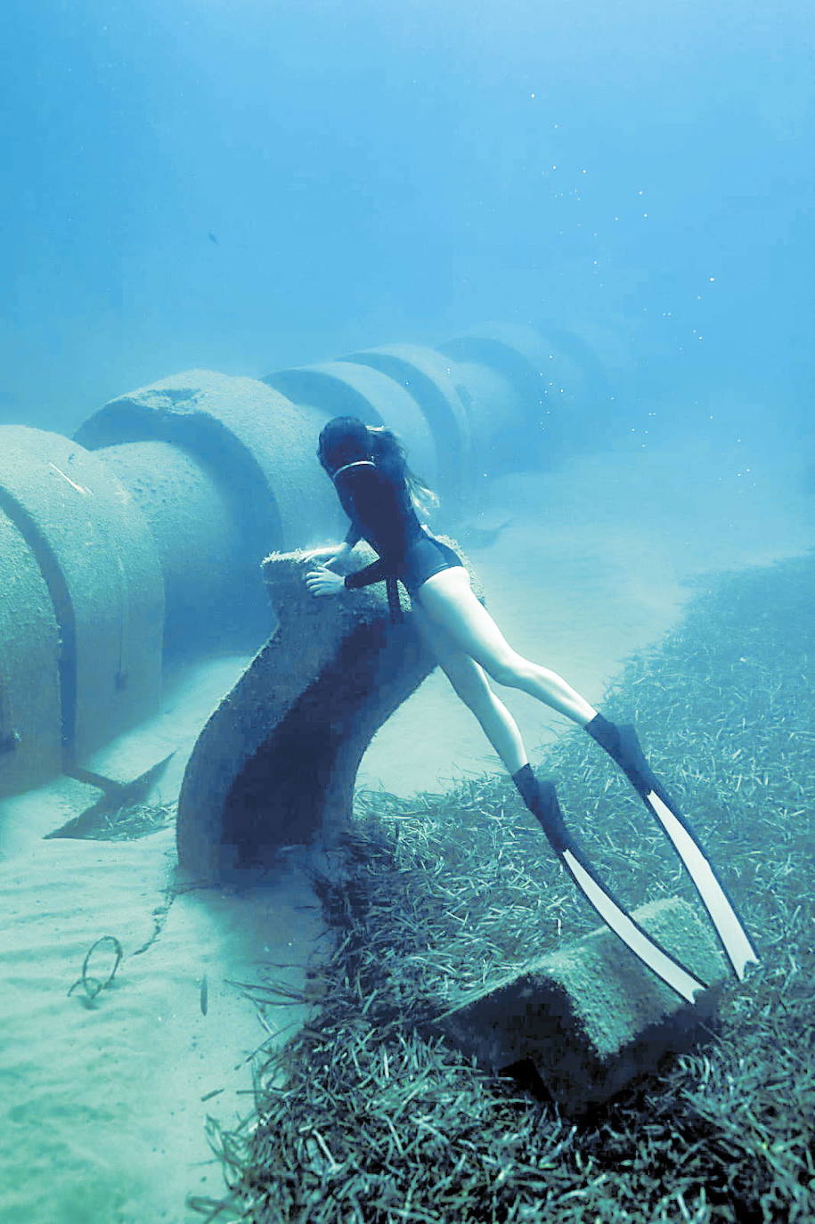 16-08-2020. Ecologistas y vecinos de Cabo de Palos denuncian el abandono en los fondos de Cala Reona de materiales de desecho de la obra del nuevo emisario. En el fondo del mar descansan los anclajes de hormigón que fijaban la antigua tubería bajo el mar. Los vecinos exigen a la Administración competente que determine quién es responsable y le obligue a limpiar la zona submarina. En la imagen, una buceadora observa los escombros en Cala Reona, junto al emisario.