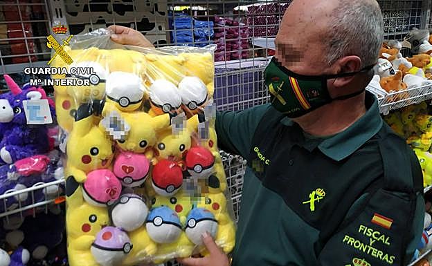 Un agente, con varios de los peluches falsificados hallados en la operación. 