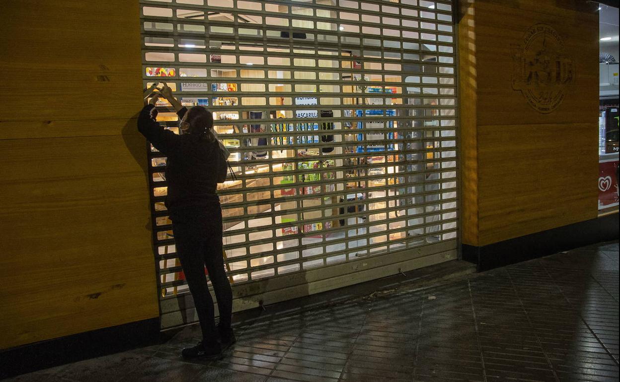 Una mujer baja la persiana de un comercio en Cartagena, en una fotografía de archivo.