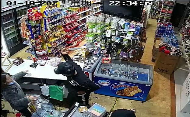 Uno de los cacos amenaza a la propietaria con el cuchillo.