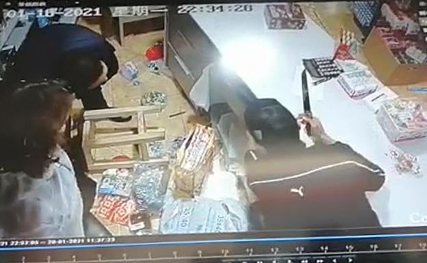 Uno de los ladrones, cuchillo en mano, coge la recaudación.