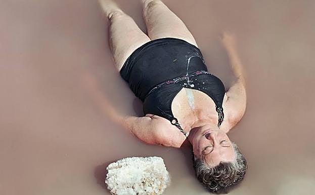 Una bañista descansa tumbada en la orilla del Mar Menor.